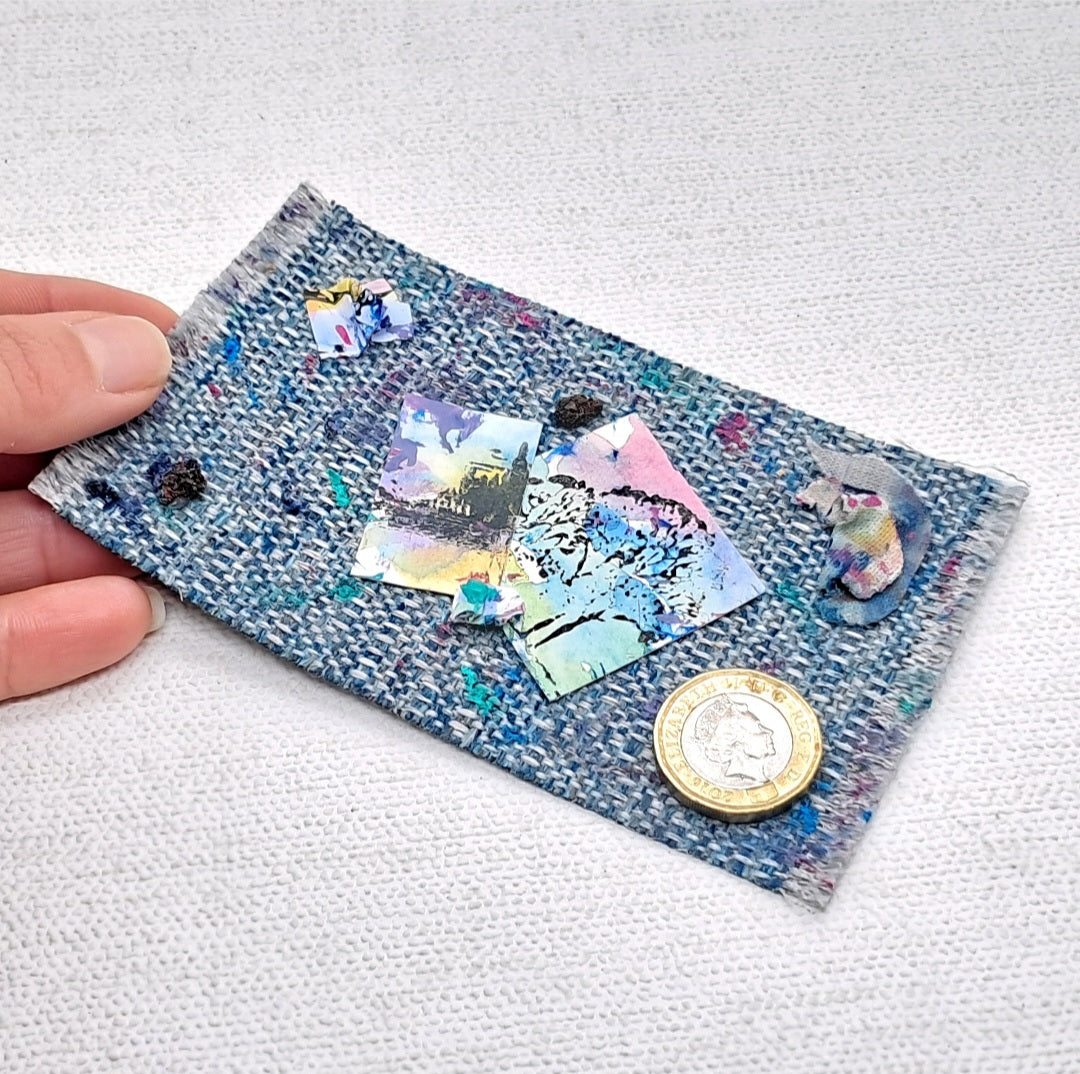 A blue dolls house rug with added messy paint stains and artworks