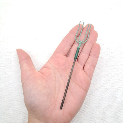 a dolls house long handled pitchfork in the 12th scale. A hand is holding it for scale purposes.